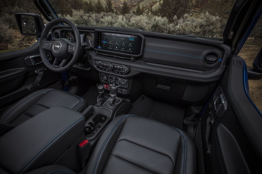 Overhead view of a Jeep Wrangler interior showing the dashboard, Uconnect touchscreen, and blue-stitched leather seats